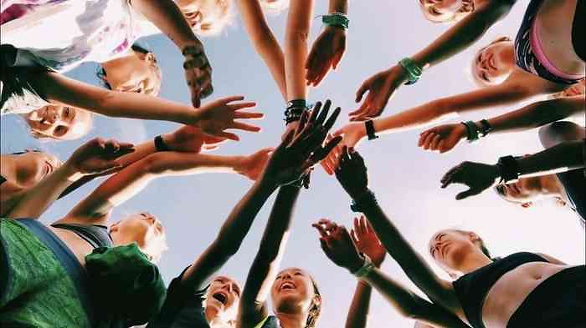 Equipo con las manos unidas en el centro de un huddle, visto desde abajo