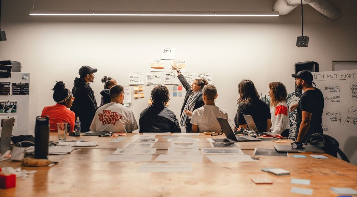 Equipo frente a una pared con notas adhesivas, una persona presentando de pie